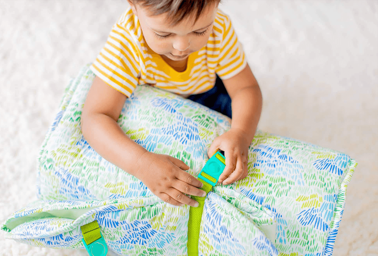 Child buckling the Nap Mat by Lovevery